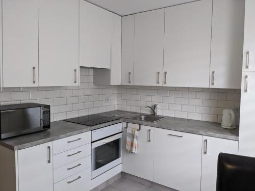 a white kitchen with white cabinets and a sink at Rigel Rooms in Piotrków Trybunalski