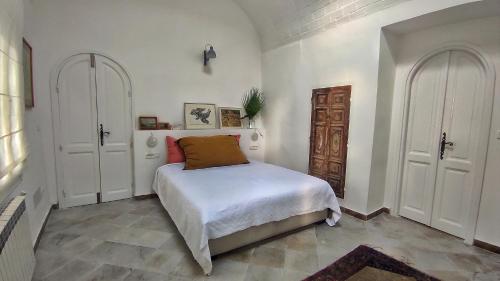 a bedroom with a bed and two white doors at Lella Zohra, Studio avec Piscine à Sidi Bou Said in Sidi Bou Saïd