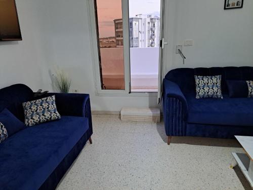 a living room with two blue couches and a window at Residence Rahma 