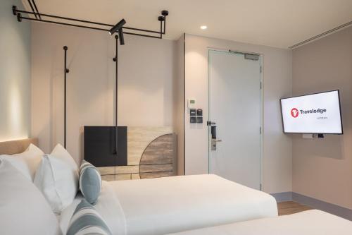 a room with two beds and a flat screen tv at Travelodge Nimman in Chiang Mai