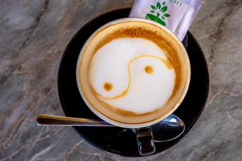 a cup of cappuccino with a smiley face drawn on top at Kalash Parkaze And Tent Inn in Pokhara