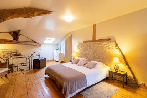 a bedroom with a large bed and a stone wall at Gite du Corupsis in Villeneuve-sur-Lot