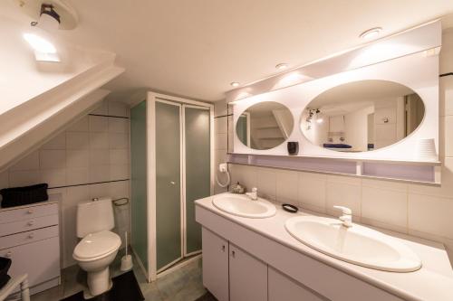 een badkamer met 2 wastafels, een toilet en een spiegel bij Gite du Corupsis in Villeneuve-sur-Lot