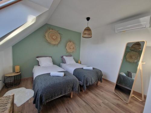 1 Schlafzimmer mit 2 Betten und einem Spiegel in der Unterkunft Chez Iris in Jebsheim