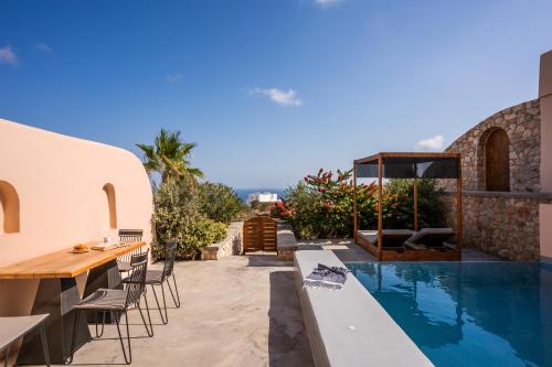 un patio al aire libre con mesa y sillas y una piscina en Perla Nera Suites, en Fira