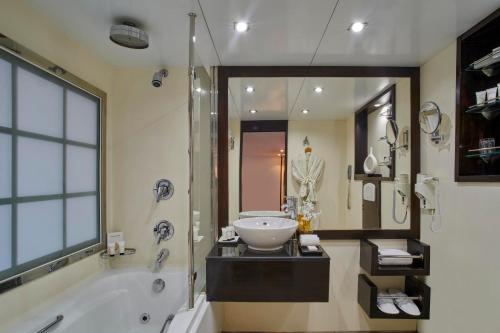 a bathroom with a tub and a sink and a shower at Mövenpick Royal Lily Monday Four Nights Luxor Friday Three Nights Aswan in Luxor