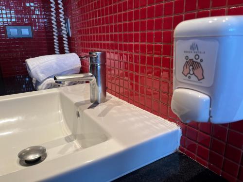 a bathroom sink with a soap dispenser next to it at Nautic Hotel & Spa in Can Pastilla