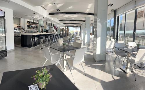 a restaurant with tables and white chairs and windows at Nautic Hotel & Spa in Can Pastilla