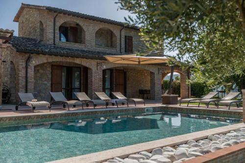 a pool with chairs and an umbrella next to a house at Villa Adriana in Valtopina