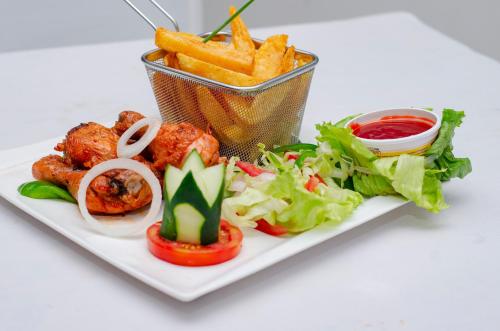 a plate of food with a basket of fries and vegetables at ROYAL SHALOM HOTEL in Lusaka