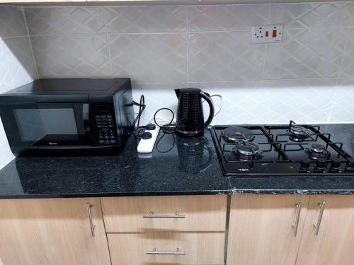 a kitchen counter with a microwave and a stove at Polea Hapa in Ngong