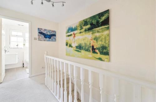 a white bathroom with a large painting on the wall at Weybridge Home in Weybridge