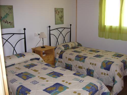 1 dormitorio con 2 camas y mesa con lámpara en Vivienda de uso turístico Fuente Vilda VT-LR 0033 en Alcanadre
