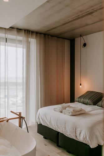 sypialnia z łóżkiem, wanną i oknem w obiekcie Suite O w Ostendzie