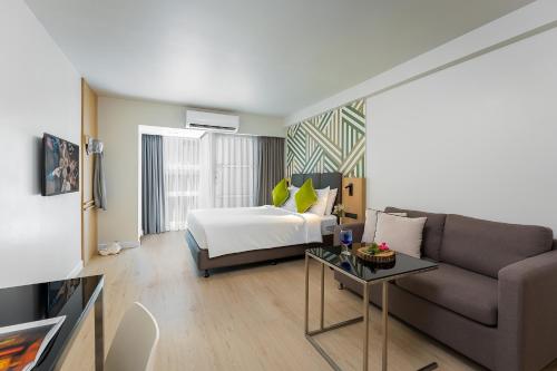 a hotel room with a bed and a couch at Citadines Sukhumvit 16 Bangkok in Bangkok