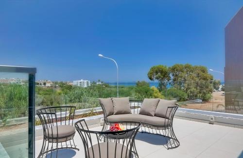 a patio with chairs and a couch on a balcony at Seaview Luxury Villa Jacuzzi & Pool! 2 Min Beach in Protaras