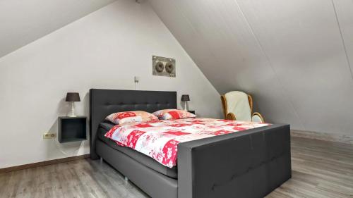 a bedroom with a black bed with a red comforter at An's Vakantiehuisje in Dessel