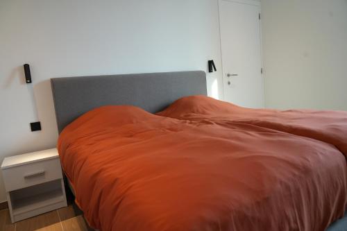 a bed with an orange blanket on top of it at ApartHotel Dénia in Lochristi