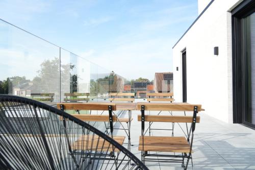 a balcony with chairs and tables on a building at ApartHotel Dénia in Lochristi