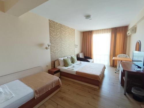 a hotel room with two beds and a desk at Семеен Хотел Детелини in Primorsko