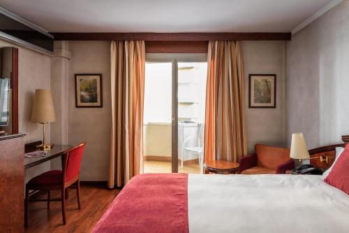 ein Hotelzimmer mit einem Bett, einem Schreibtisch und einem Stuhl in der Unterkunft ALEGRIA President in Andorra la Vella