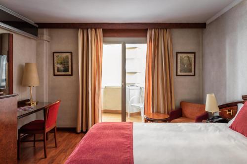 Cette chambre comprend un lit, un bureau et une chaise. dans l'établissement ALEGRIA President, à Andorre-la-Vieille
