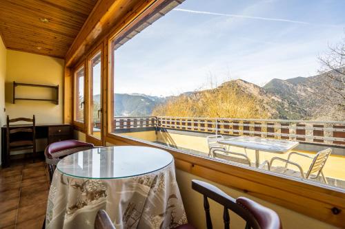 a room with a table and chairs and a large window at Abba Ordino Babot Hotel in Ordino