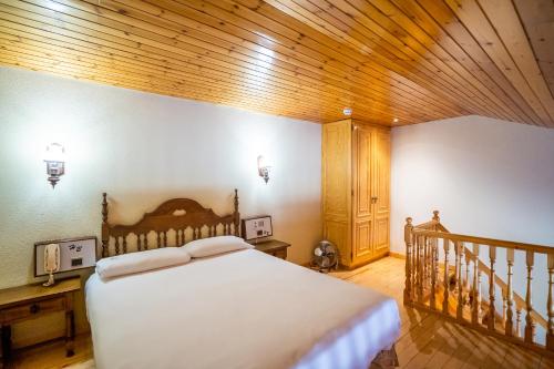 a bedroom with a bed and a wooden ceiling at Abba Ordino Babot Hotel in Ordino