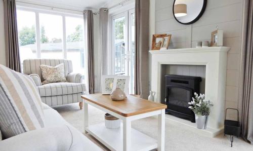 a living room with a fireplace and a table at Newperran Holiday Park in Newquay