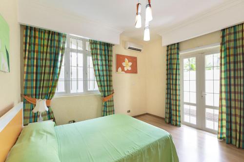 a bedroom with a green bed and windows at Apartment Orchid in Mont Choisy