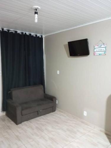 Zimmer mit Sofa und TV an der Wand in der Unterkunft Cabana 2 qts com Ar-condicionado in Machadinho