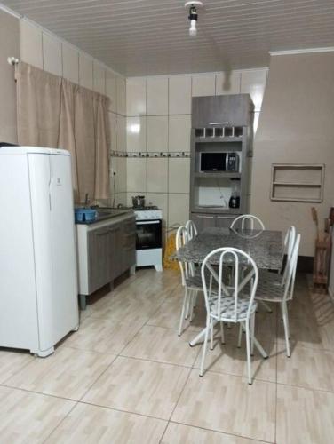 eine Küche mit einem Tisch und Stühlen sowie einem Kühlschrank in der Unterkunft Cabana 2 qts com Ar-condicionado in Machadinho