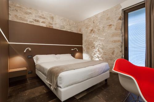 a bedroom with a large bed and a red chair at Villa Boscarino Boutique Hotel & Spa in Ragusa