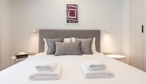 1 dormitorio con 1 cama blanca y 2 toallas en Athens Theatrou Apartments, en Atenas