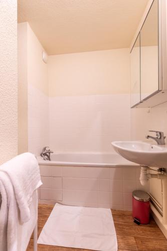 une salle de bain blanche avec un lavabo et une baignoire dans l'établissement Résidence Les Dômes, à Royat