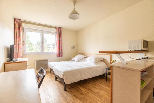 une chambre d'hôtel avec un lit et un bureau dans l'établissement Résidence Les Dômes, à Royat