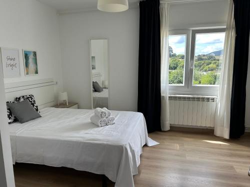 a white bedroom with a bed and a window at Apartagal-A Corredoira in Foz