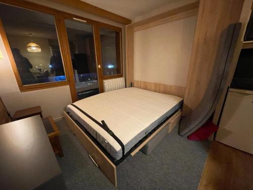 a small bed in a small room with a window at Studio 941-Particulier-Résidence L'Ours Blanc-Alpe d'Huez-Centre Station in L'Alpe-d'Huez