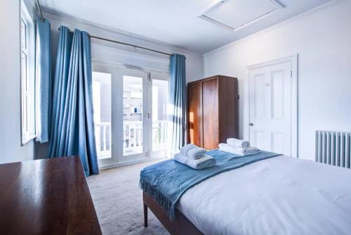 1 dormitorio con 1 cama grande y cortinas azules en Pass the Keys Large house Leigh Sea views en Southend-on-Sea
