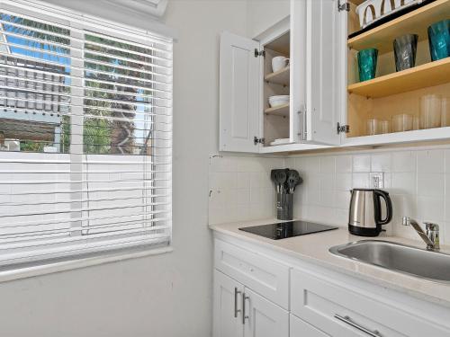 a kitchen with white cabinets and a sink and a window at Siesta By The Beach in Pompano Beach