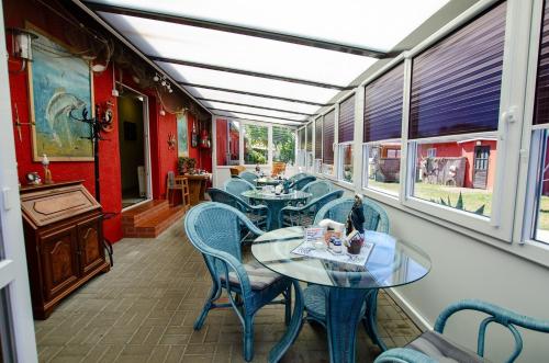 un restaurant avec des tables, des chaises et des fenêtres dans l'établissement Familienzimmer-mit-Gemeinschaftsbad-fuer-4-Personen-auf-Ruegen-H5Zi2, à Rappin