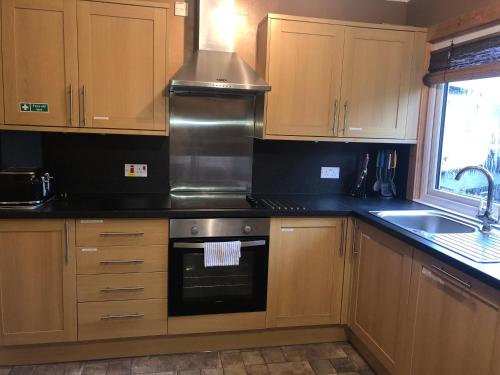 a kitchen with wooden cabinets and a stove top oven at Number 12 Self Catering in Portree