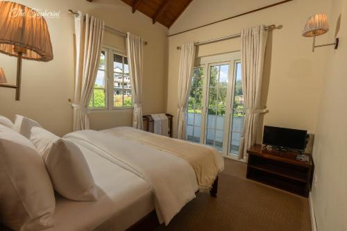 a bedroom with a bed and a television and a window at The Tapherini Bungalow in Nuwara Eliya