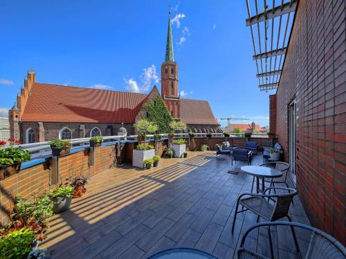 eine Terrasse mit Tischen und Stühlen vor einer Kirche in der Unterkunft Mercure Wrocław Centrum in Breslau
