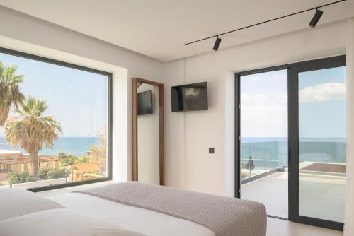 a bedroom with a bed and large glass windows at Asea Villa, Spectacular right-on-the-beach Retreat, By ThinkVilla in Skaleta
