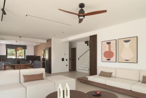 a living room with white furniture and a ceiling fan at Asea Villa, Spectacular right-on-the-beach Retreat, By ThinkVilla in Skaleta