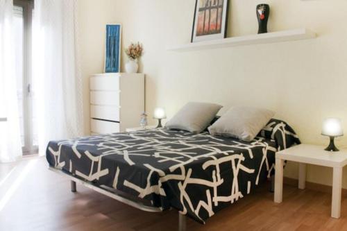 une chambre avec un lit avec une couette noire et blanche dans l'établissement Apartamento Cerca del Mar, à Badalona