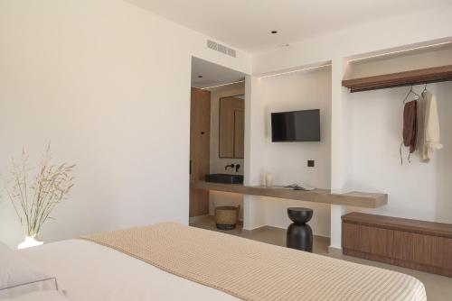 a bedroom with a bed and a desk with a television at Asea Villa, Spectacular right-on-the-beach Retreat, By ThinkVilla in Skaleta
