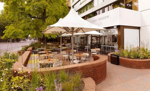 un restaurante con mesas, sillas y sombrilla en DoubleTree by Hilton London - Hyde Park en Londres