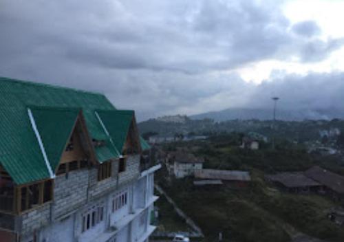ein Gebäude mit einem grünen Dach in einer Stadt in der Unterkunft Hotel North Hill Arunachal Pradesh in Tawang